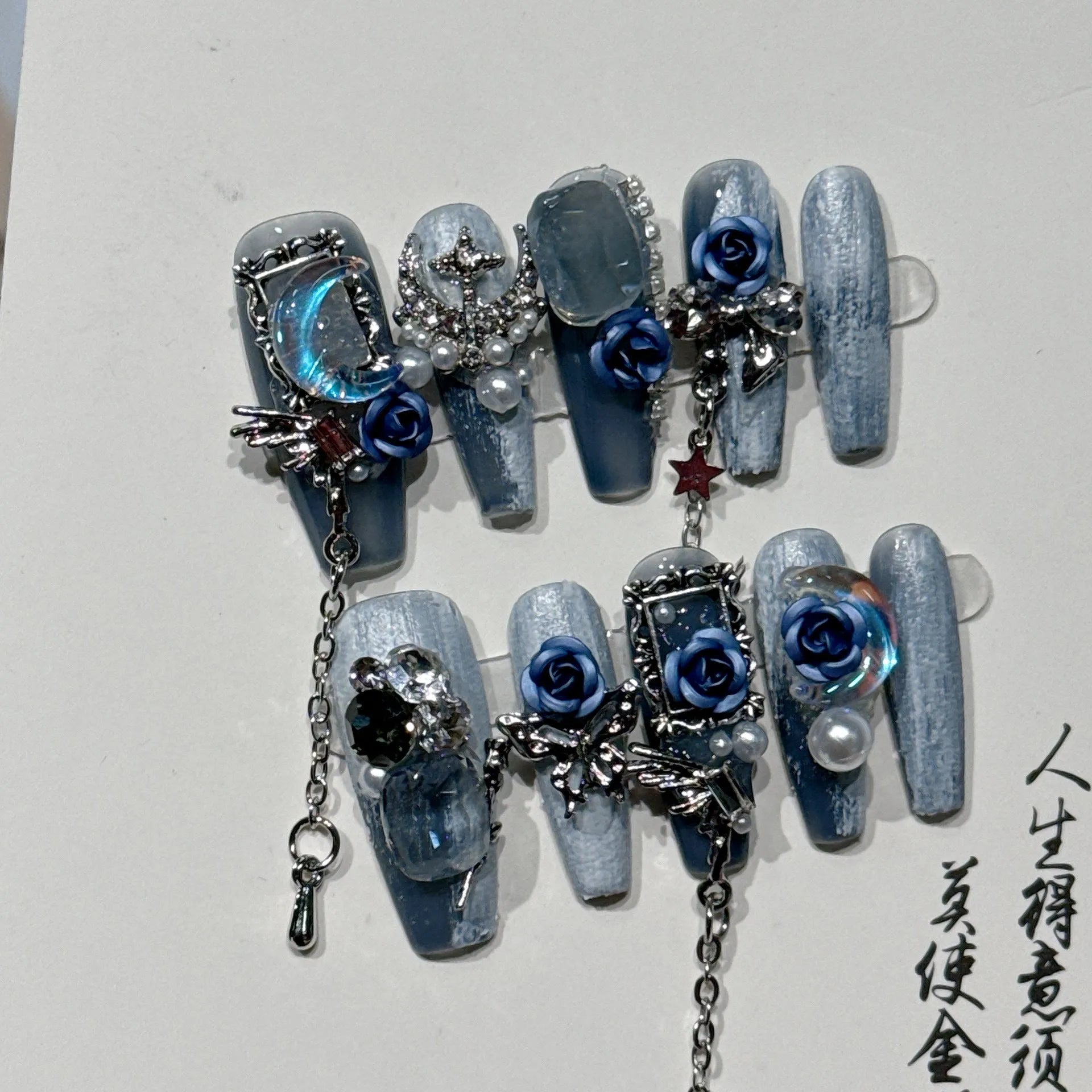 False nails with ornate rose and floral pattern in dark blue, showing sizes XS, S, M, L.