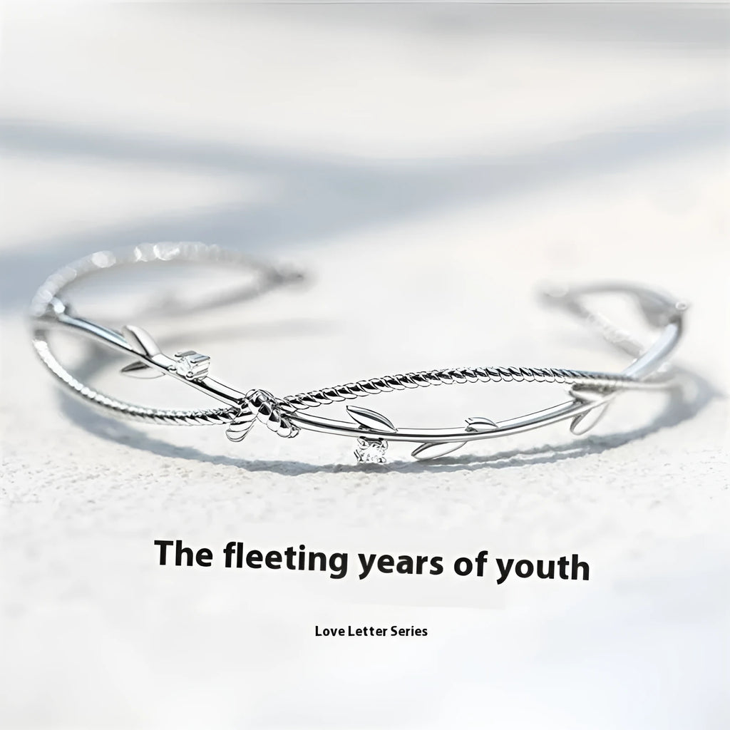 White gold sprout branch bracelet with cross twisted design on a wrist.