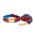 Blue background velvet plaid dog collar and matching hand holding leash on a white surface.