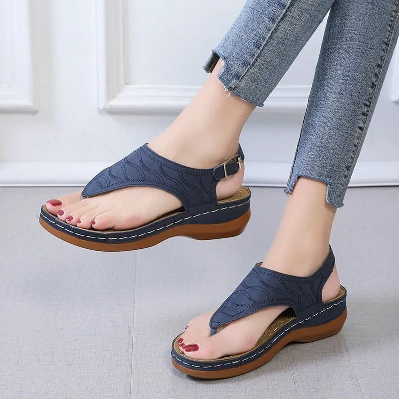 Women's black wedge heel sandals with an adjustable buckle back strap on a plain background.