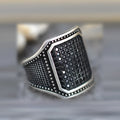 Black geometric alloy ring with copper inlay and zircon stone details on a finger.