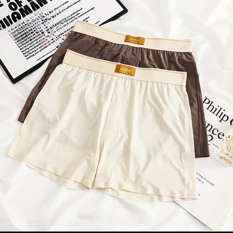 Three pairs of solid colour men's loose fit ice silk boxers laid flat, showing beige apricot, black, and dark grey.