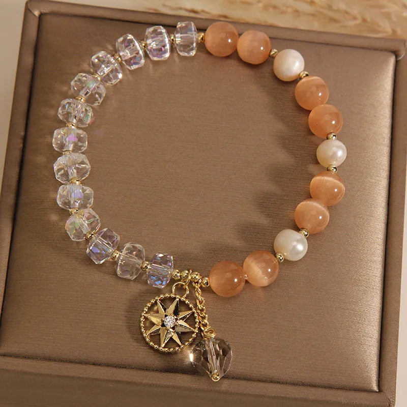 Women's gold-plated bracelet with an eight-pointed star design and a central inlaid orange opal crystal.