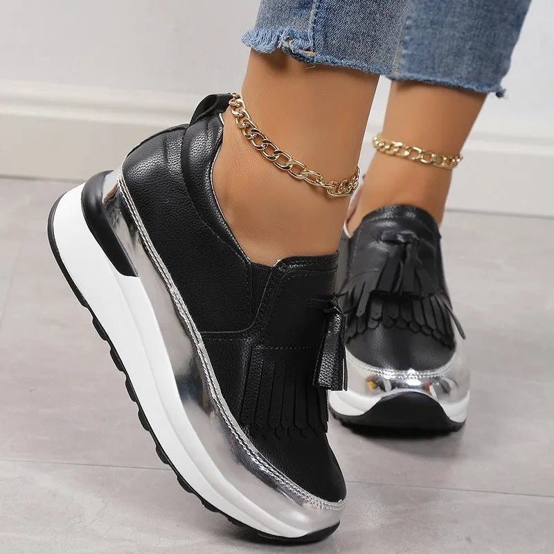 Women's black casual platform shoes with a tassel and distinctive muffin wedge heel on a white background.