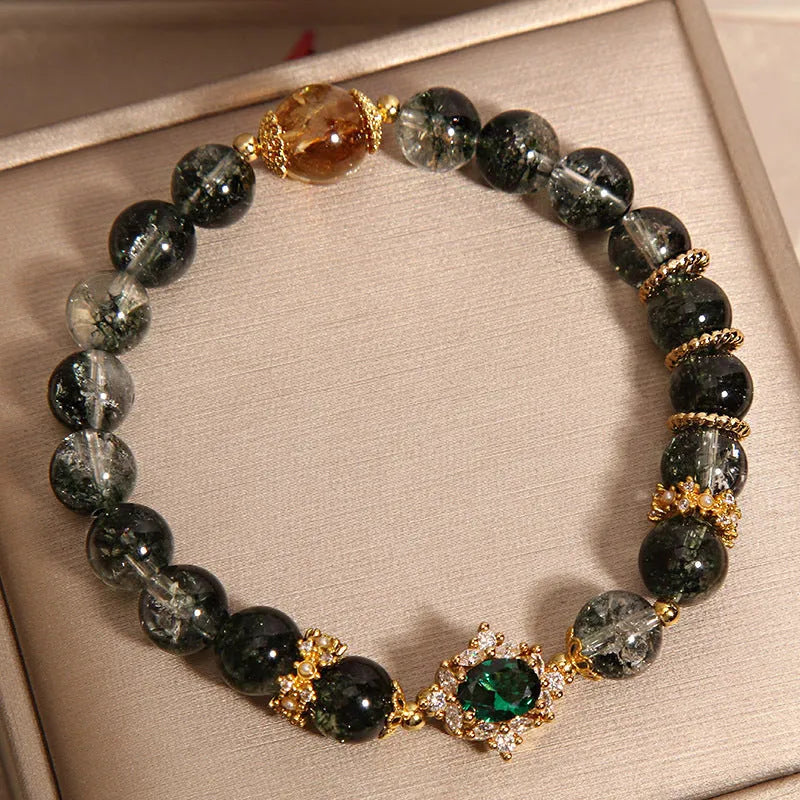 Women's green phantom quartz crystal bracelet with gold rutile needles, ruby quartz bead, pearls, and rhinestone details.