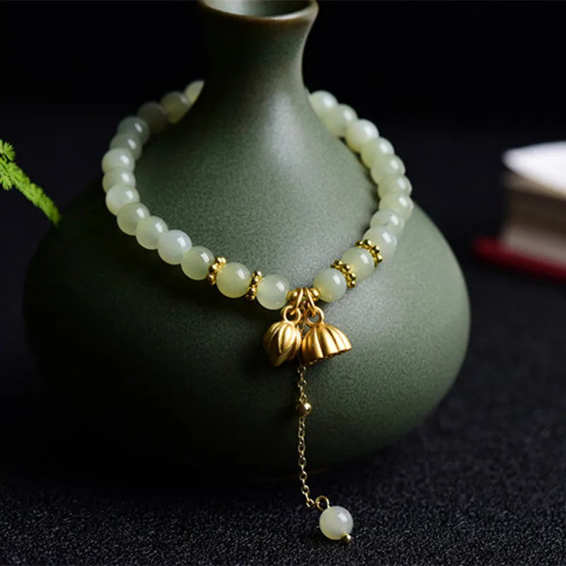 Natural Hetian jade bracelet with a carved Fu character charm on a wrist.