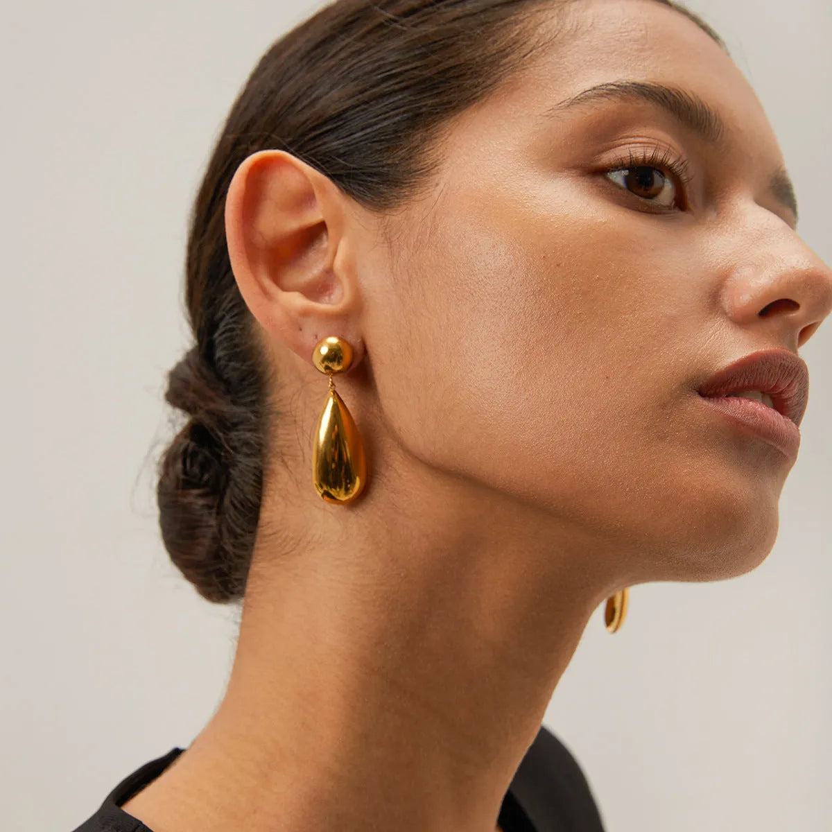 A pair of gold-coloured hemisphere-shaped earrings with a water drop pendant design, made from stainless steel.