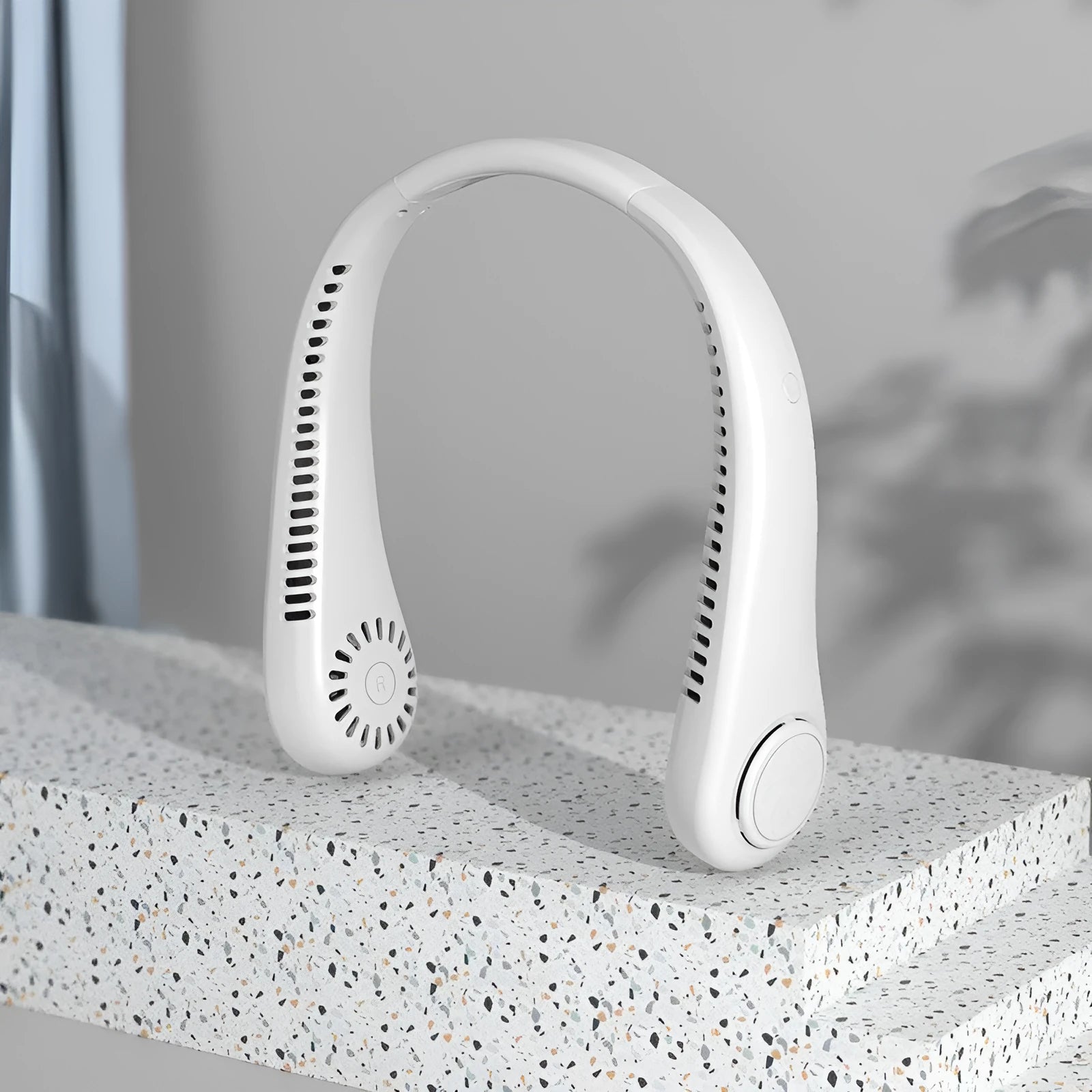 White portable bladeless neck fan hanging around a person's neck showing its USB charging port.