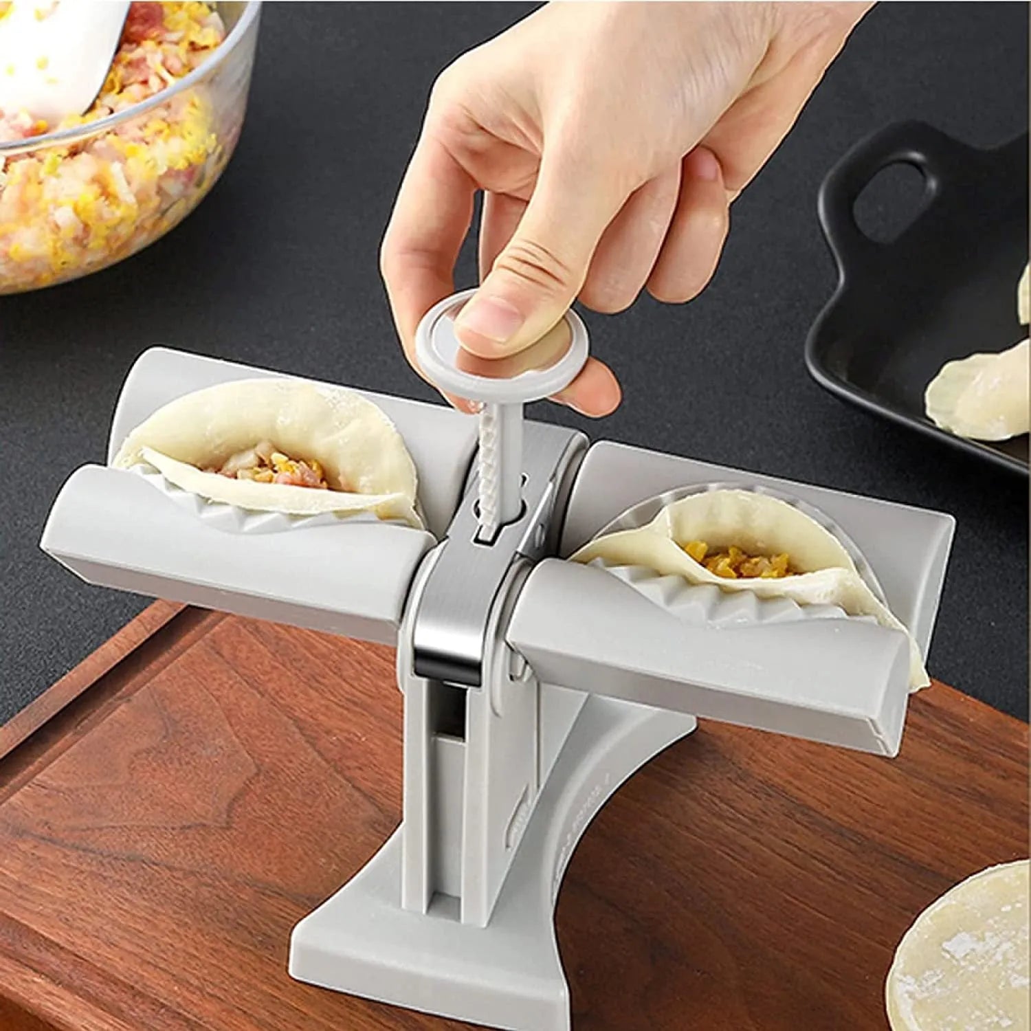 White double-head manual dumpling mould with stainless steel and plastic construction on a rubber anti-slip mat.