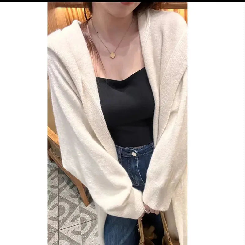 A woman wearing a long, loose, hooded knitted cardigan in a solid colour, demonstrating its below-the-knee length.