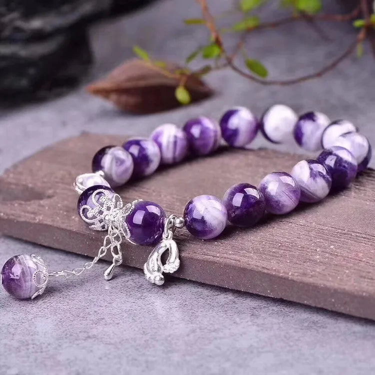 Close-up of a natural amethyst bracelet with 10mm round purple beads on a wrist.