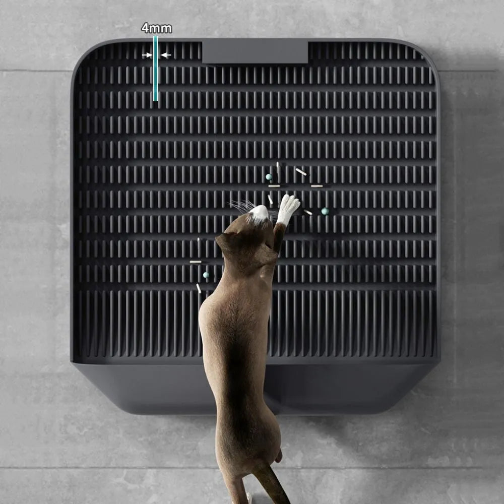 Large black cat litter pedal mat with textured grooves, placed next to a litter box.