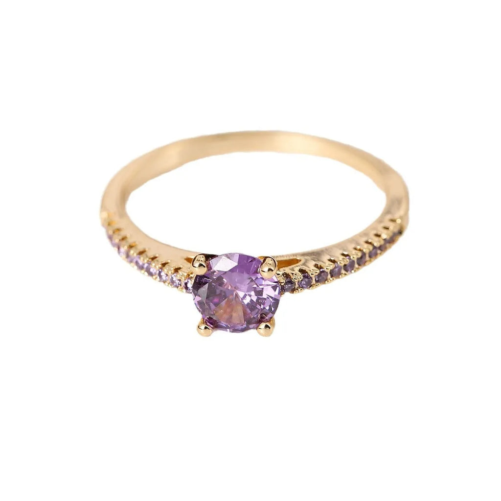 Colourful hexagon zircon copper ring in gold and gun black finishes on a size guide.