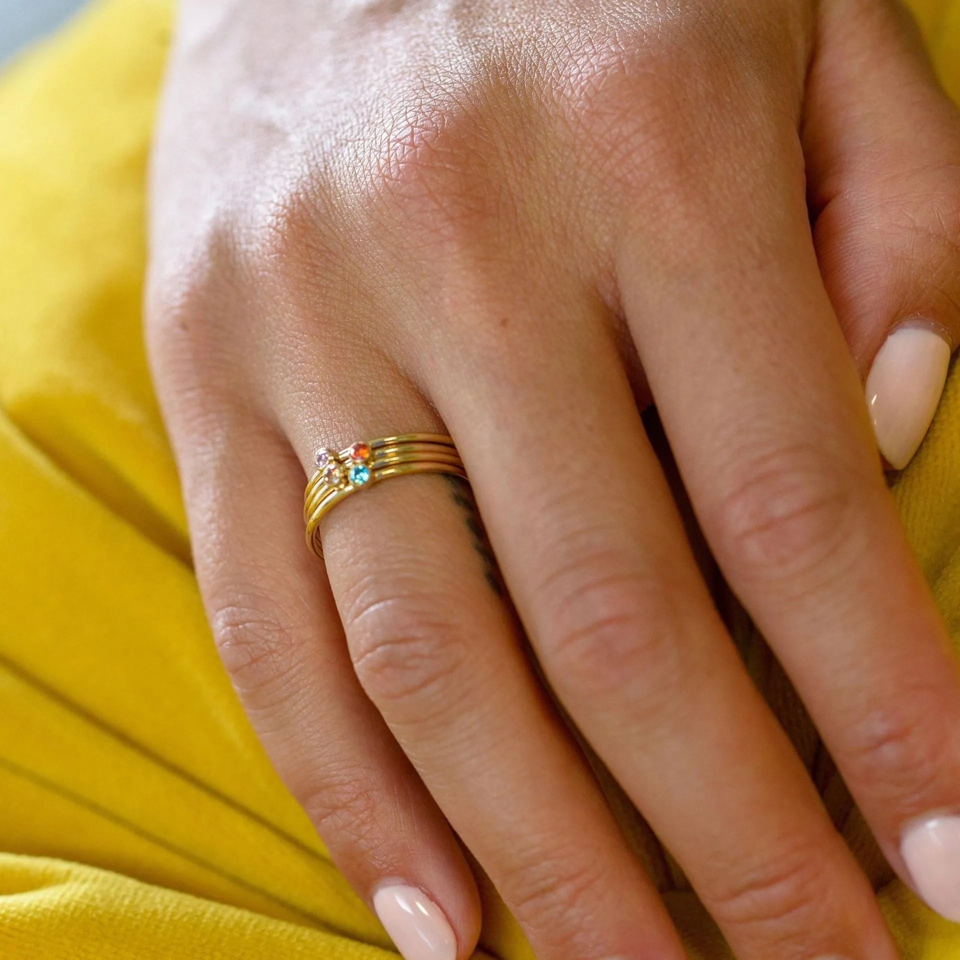 Close-up of a titanium steel ring with an engraved geometric design and a December colour birthstone.