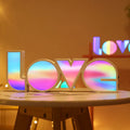 LED Love light with rainbow 'LOVE' lampshade on a table.