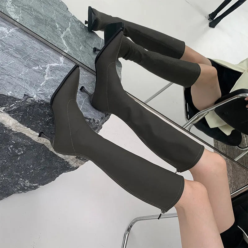 Black women's pointed toe below knee boots with a stiletto heel and a back zip.