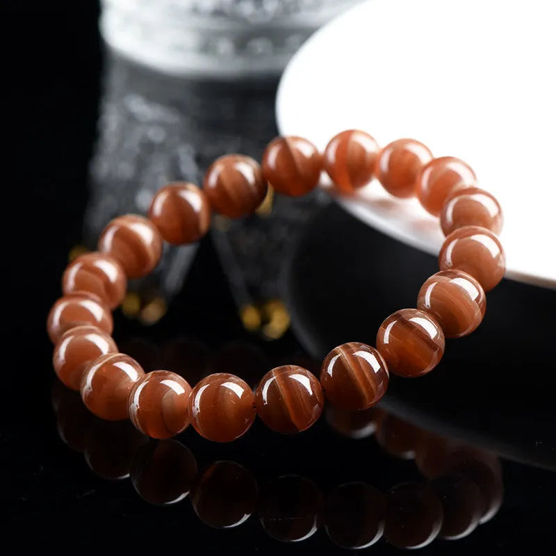 Natural old mine rhodochrosite bracelet with geometric beads and Ruyi symbols on a wrist.