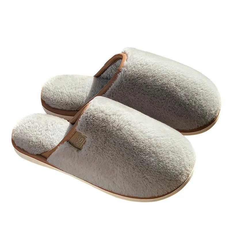 Blue winter plush slippers with non-slip PVC soles on a wooden floor.