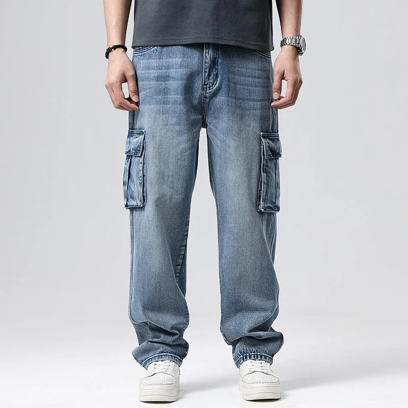 Man wearing loose-fit blue denim hip hop trousers with multiple pockets and a straight leg.