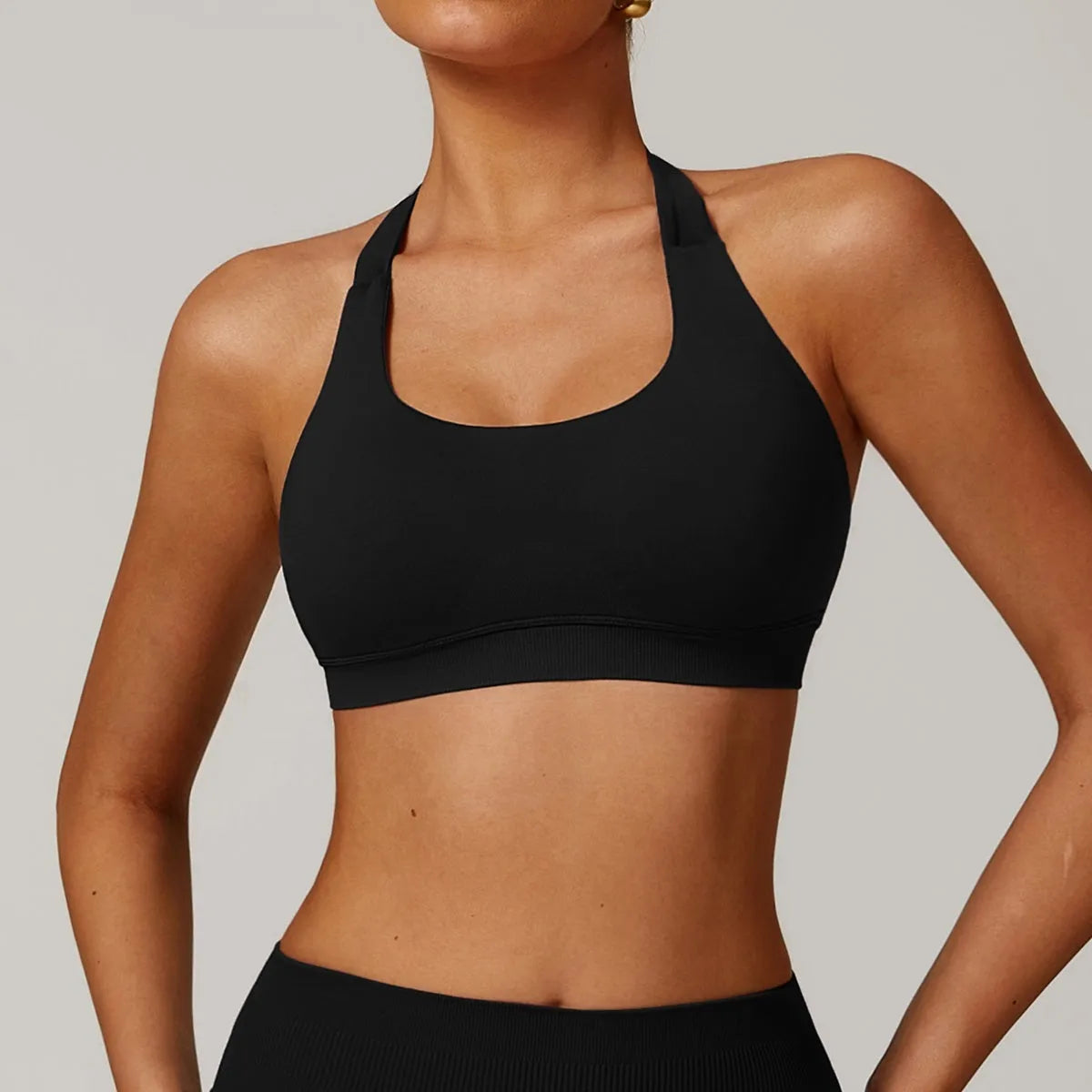 Women's black halter style sports bra with hollow cut and chest pads on a mannequin.