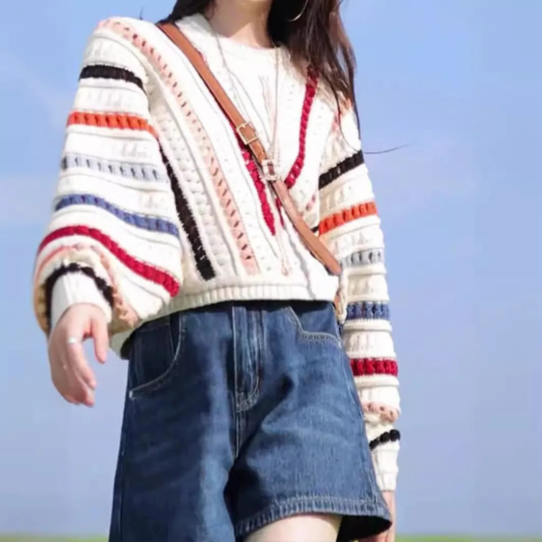 Colourful rainbow striped loose fit pullover sweater with batwing sleeves on a neutral background.
