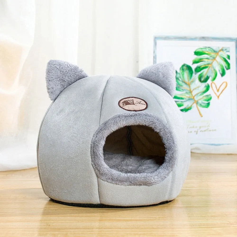 A fully enclosed cube-shaped cat sofa nest, showing the entrance hole, in a home setting.