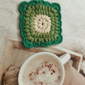 Crocheted wool cup placemat with grandmother lattice pattern in a choice of four colours.