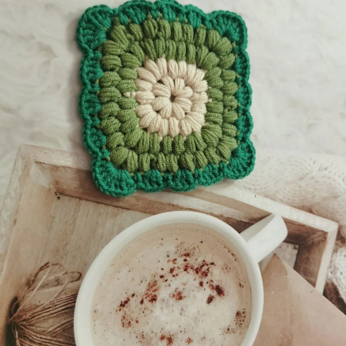 Crocheted wool cup placemat with grandmother lattice pattern in a choice of four colours.