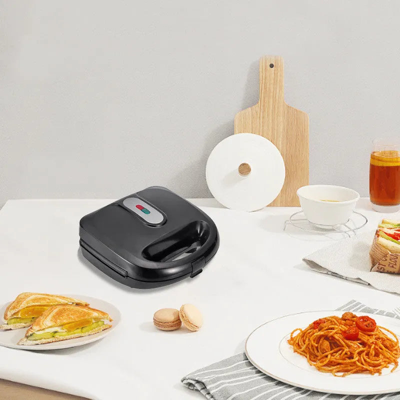 Black double-sided electric sandwich pan with stainless steel lid and six non-stick baking pans.