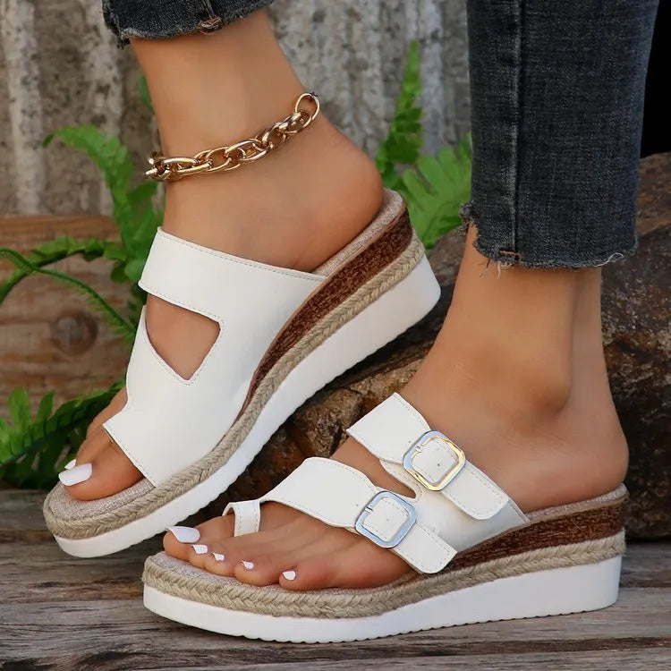 White patent leather wedge sandals with woven finger-fit straps and a peep toe design on a rubber sole.