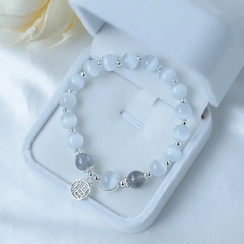 Women's opal cat's eye stone bracelet with diamond-shaped beads on wrist.