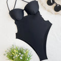 Black solid colour one-piece swimsuit for women on a hanger, showing v-neck design.