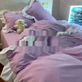 Washed cotton four-piece bedding set in a soft solid colour, showing quilt cover and pillowcases on a bed.