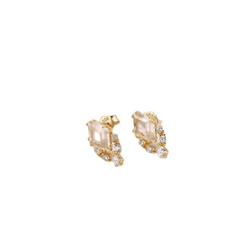 A pair of geometric shaped silver ear studs with sweet white crystal centres on a plain background.