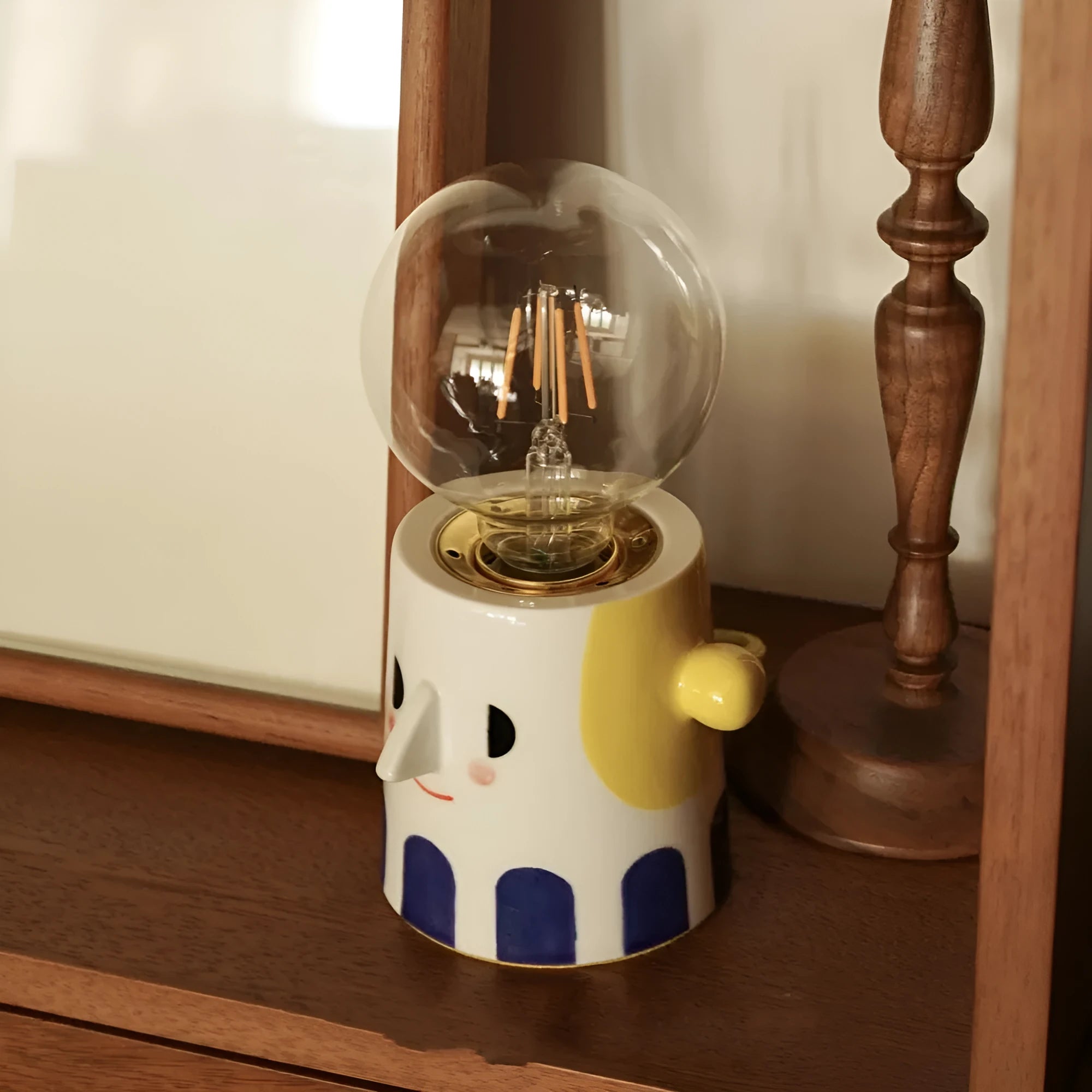 Handmade ceramic bedside lamp with a ball headlight colour finish on a table.