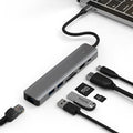 Silver 7-in-1 USB-C hub showing USB-C PD port, three USB ports, HDMI, and SD card slots.
