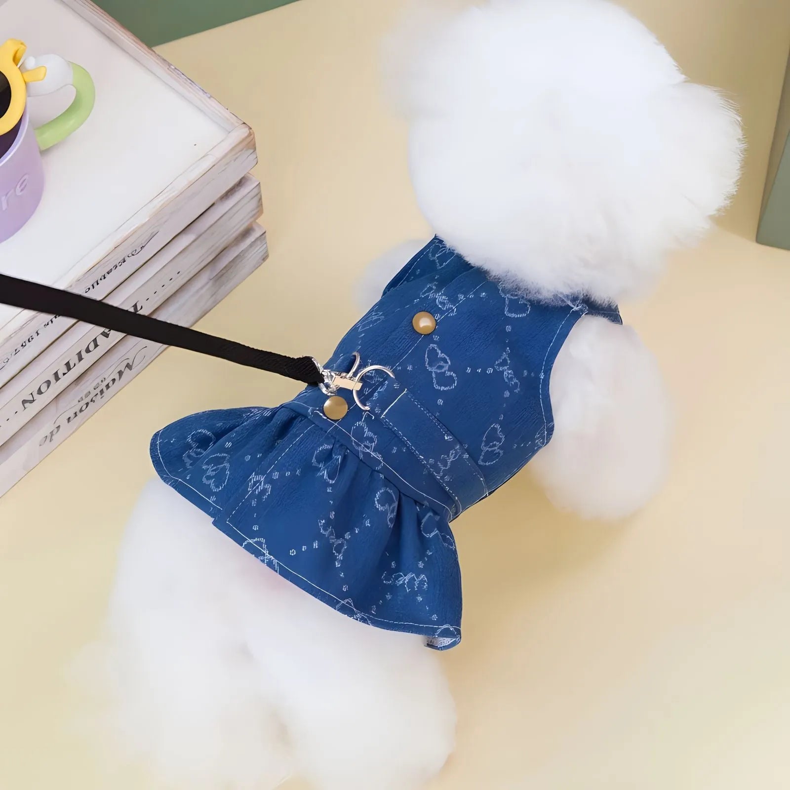 Small white dog wearing a light blue denim princess dress with a frilled skirt.