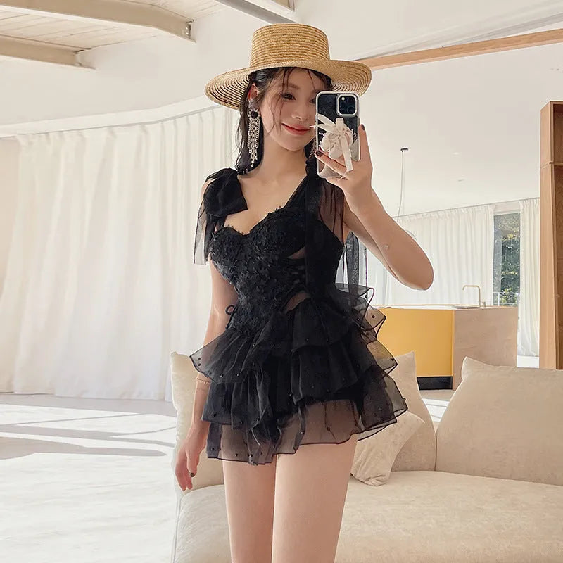 Black one-piece swimsuit with gathered chest design on a model, showing conservative sleeveless cut.
