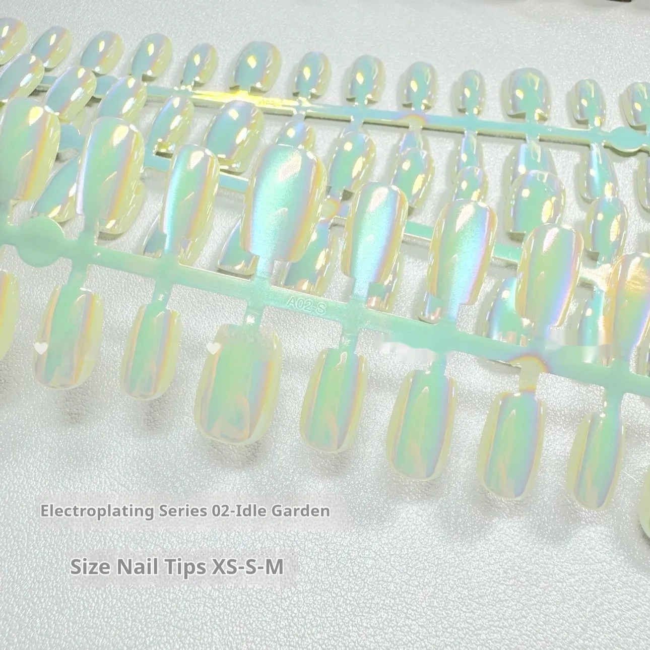 Set of electroplated Cat's Eye false nails in short ladder almond shape on a blue background, showing Aurora armour and solid colour designs.