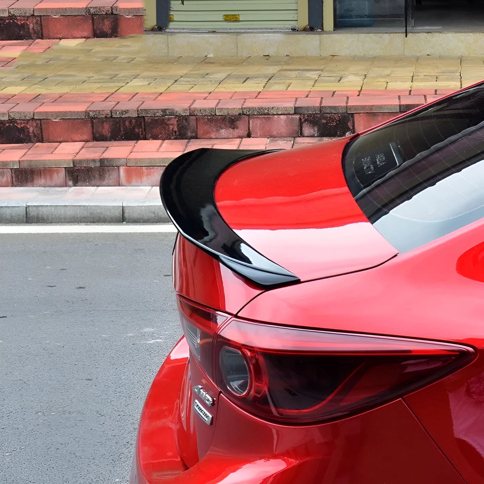 Bright black modified tail trim for Mazda 3 Exela 2014-2021 models showing large fixed wind surround design