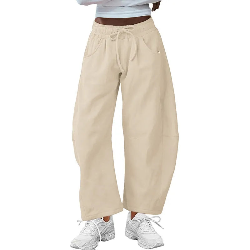 Woman wearing loose light grey cropped sweatpants with drawstring waist and side pockets