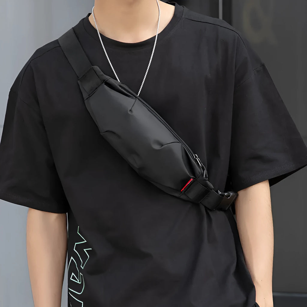 Black oxford cloth crossbody waist pack showing front zipper and strap.