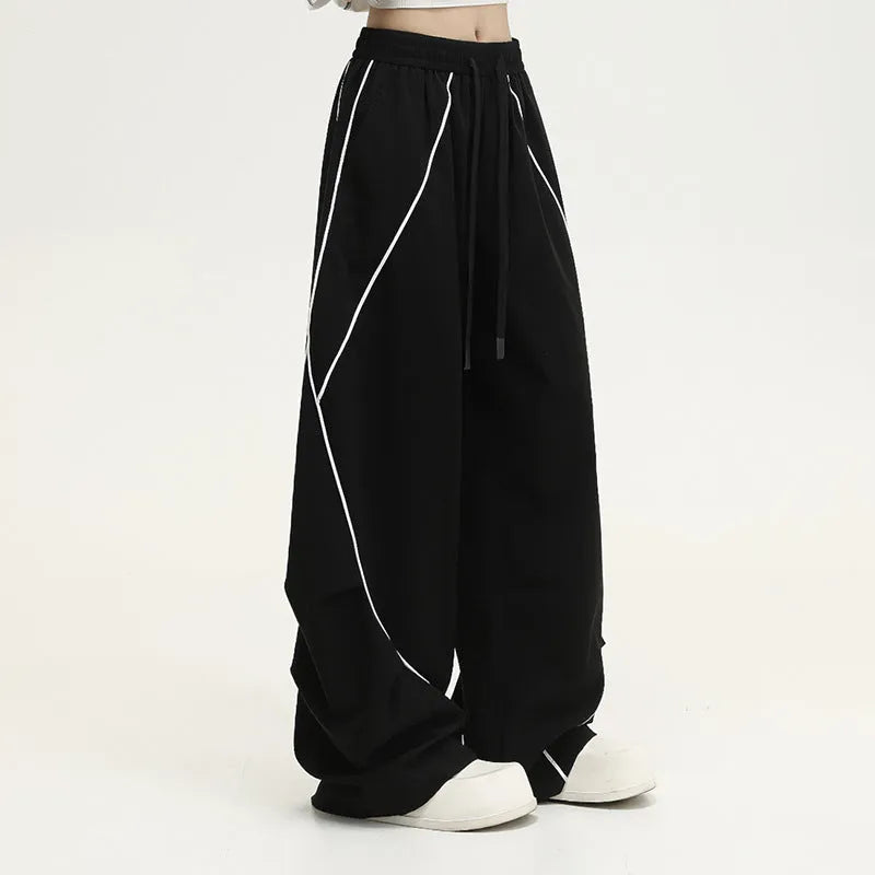 Black striped wide-leg pleated sports trousers showing loose fit and mid-waist design