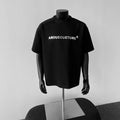 Man wearing a light grey short sleeve pullover shirt with a loose fit and black letter graphic.