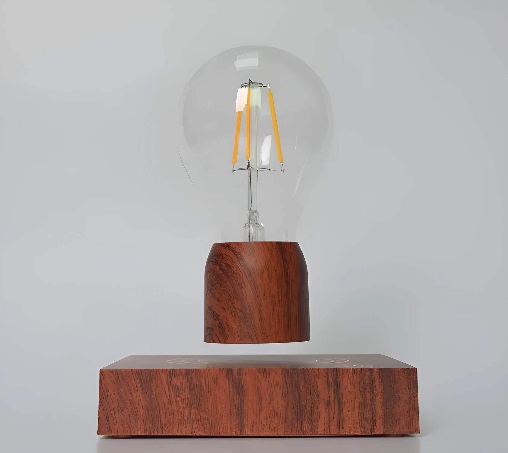 Magnetic levitation floating LED light bulb above an imitation wood base.