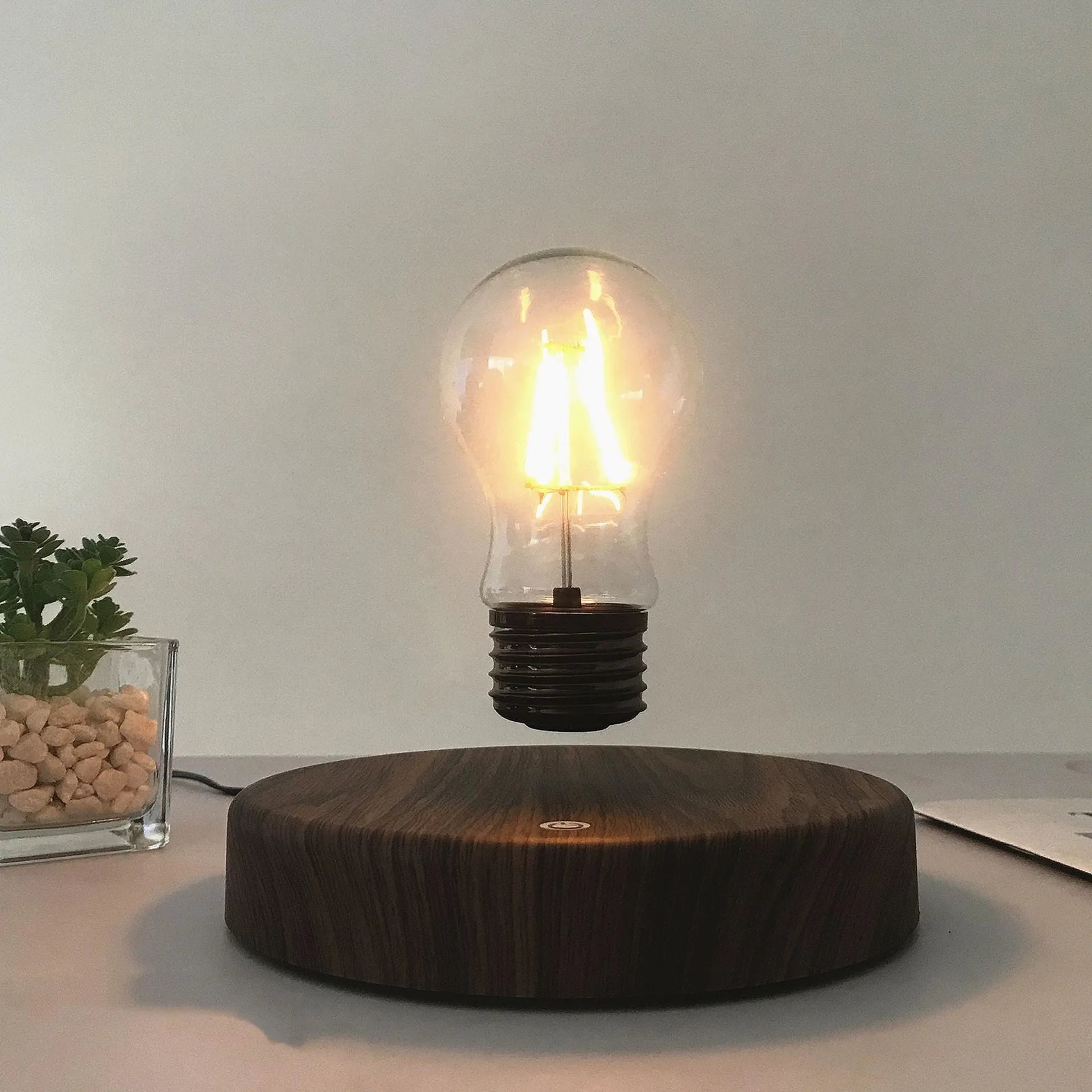 Magnetic levitation bulb night light in solid wood colour with UK plug on a desk.