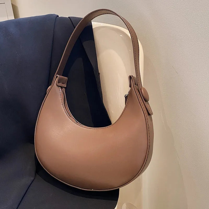 Women's retro dumpling-shaped shoulder bag in PU, shown in one of four colours, featuring an outer pocket and internal zipper compartment.
