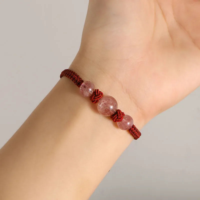 Woven red rope bracelet with spherical strawberry quartz or obsidian beads and an alloy clasp.