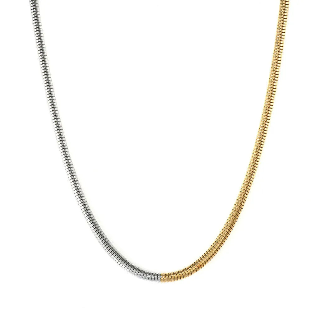 Cold golden 3mm wide stainless steel snake bones chain necklace on a flat surface.