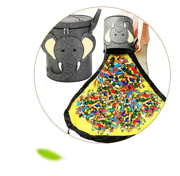 Green felt cube-shaped toy storage bag opened flat as a play mat next to toys, showing pull rope.